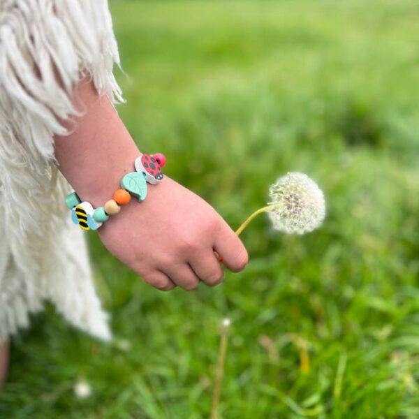 Kind mit Waldtier-Armband auf einer Wiese